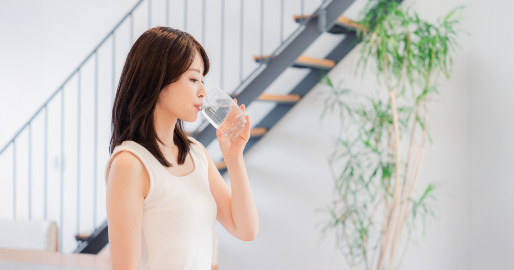 女性がガラスのコップで水を飲んでいる様子