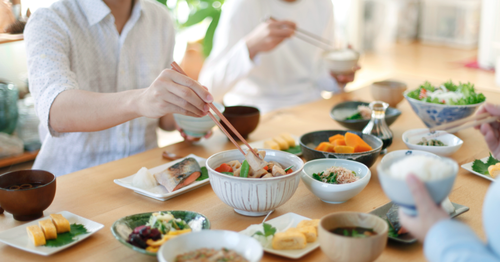食卓を囲んで日本の家庭料理を食べている画像