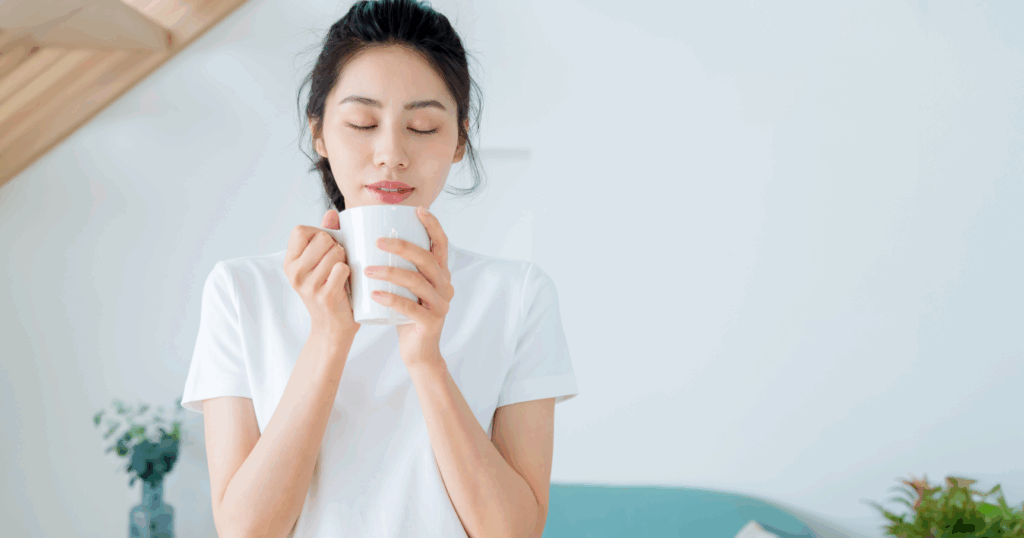 女性が両手でティーカップに入れた白湯を持っている写真