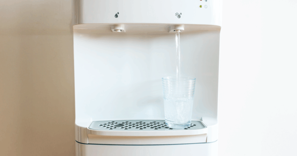 ウォーターサーバーからガラスのコップに水が注がれている写真