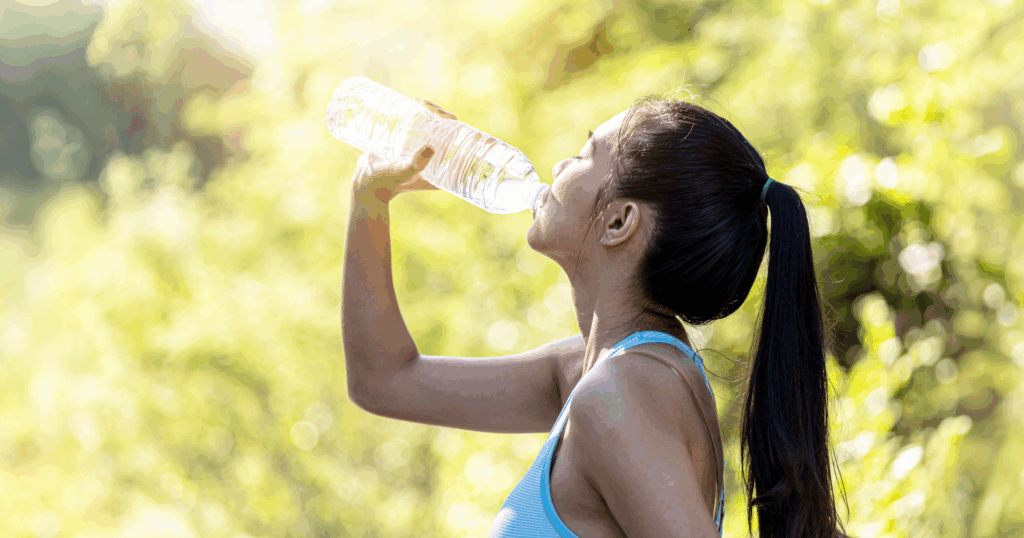スポーツウェアの女性が運動後にペットボトルから水分補給している様子