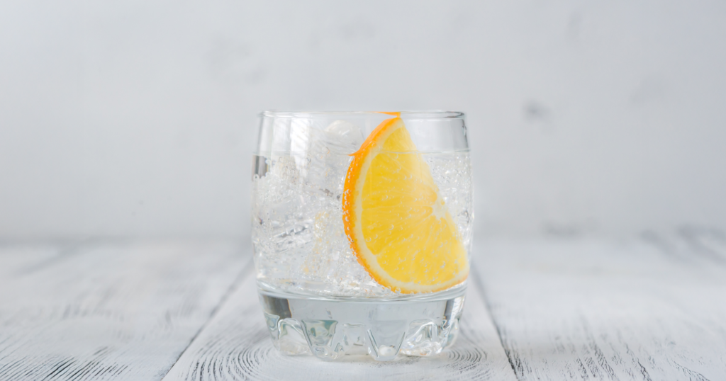 木の机に置かれた、ガラスに入ったオレンジ入り炭酸水。