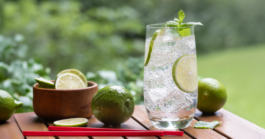 屋外の木の机に置かれた、ガラスのコップに入ったカボス入り炭酸水。