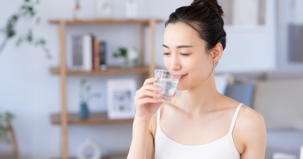 女性が家の中でガラスに入った水を飲む様子