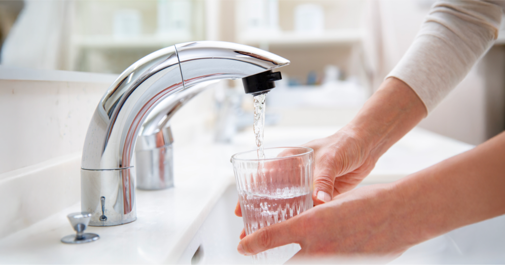 洗面所で蛇口から出る水をコップに注ぐ女性の手