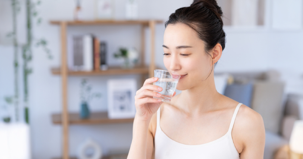 家の中で女性がガラスのコップから水を飲む様子