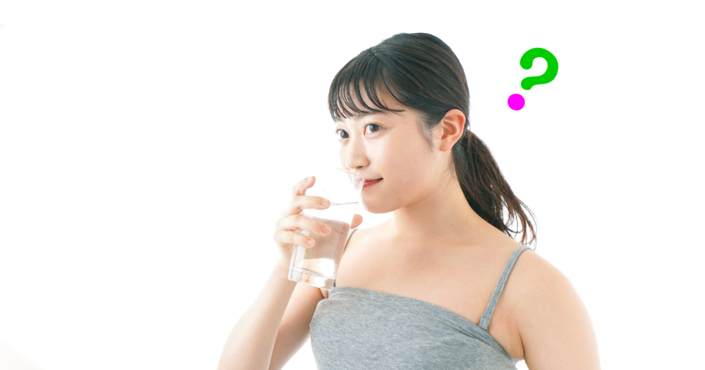 タンクトップ姿の女性がガラスのコップに入った水を飲む様子。頭の近くにハテナマークが浮かんでいる。