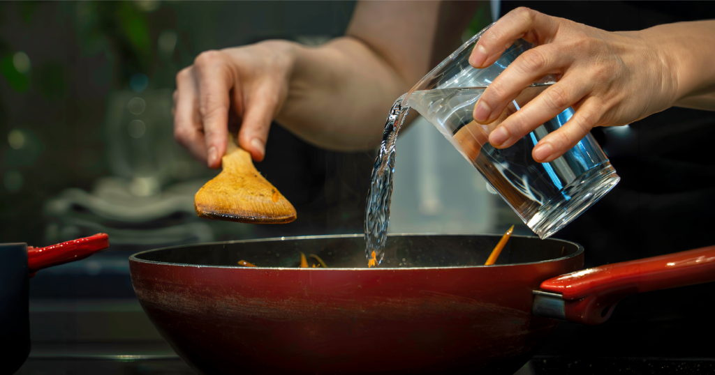 料理中のフライパンにアルカリ性イオン水を注いでいる様子