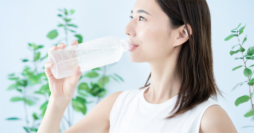 女性がペットボトルに入った水を飲んでいる様子