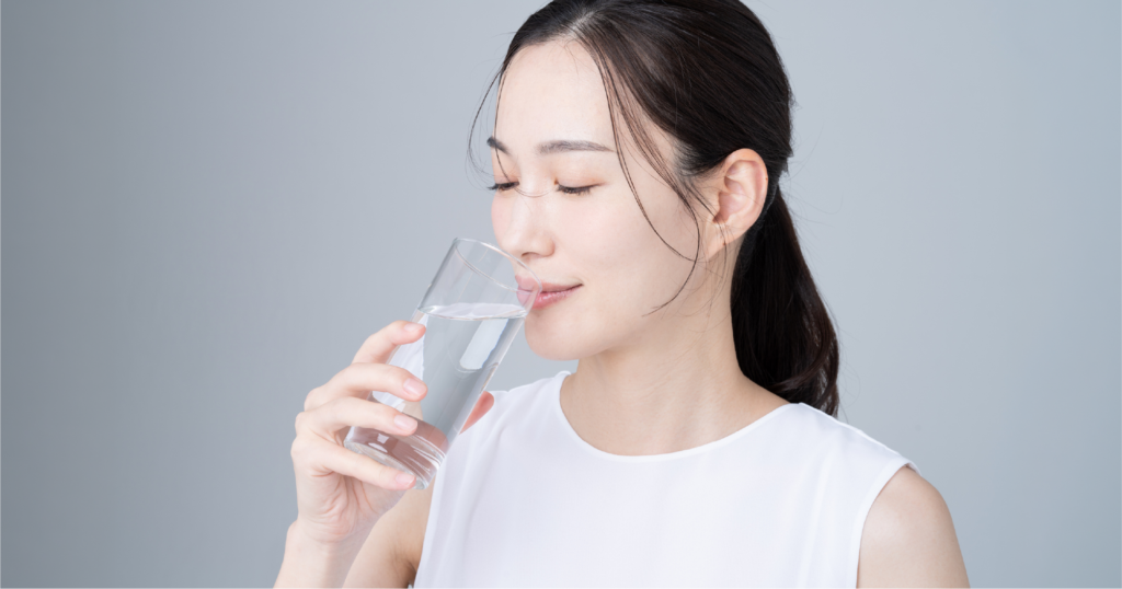 女性がガラスに入った水を飲んでいる様子