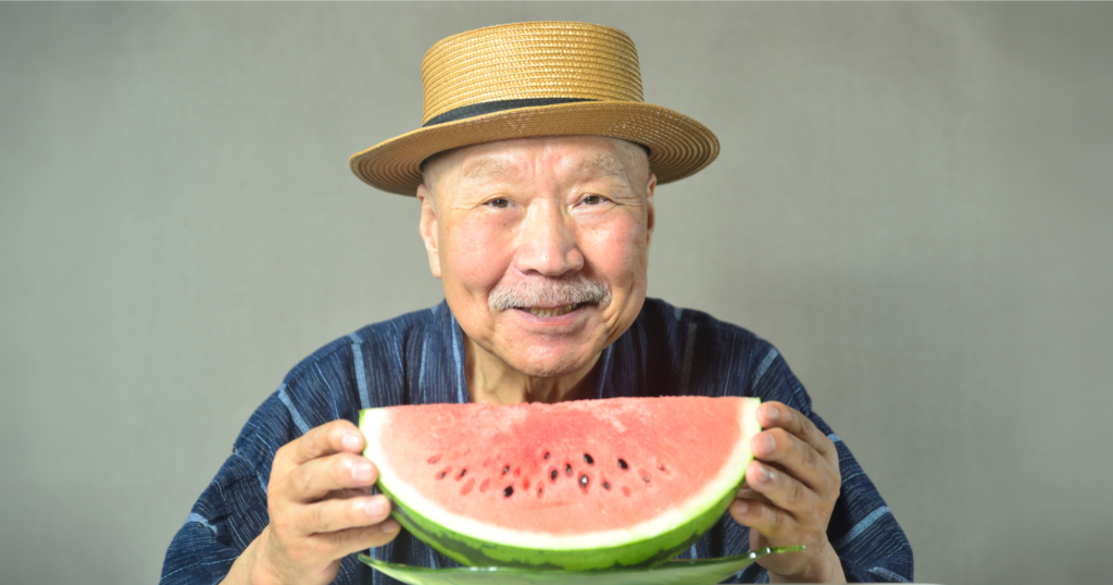 高齢男性がスイカを手に微笑んでいる写真