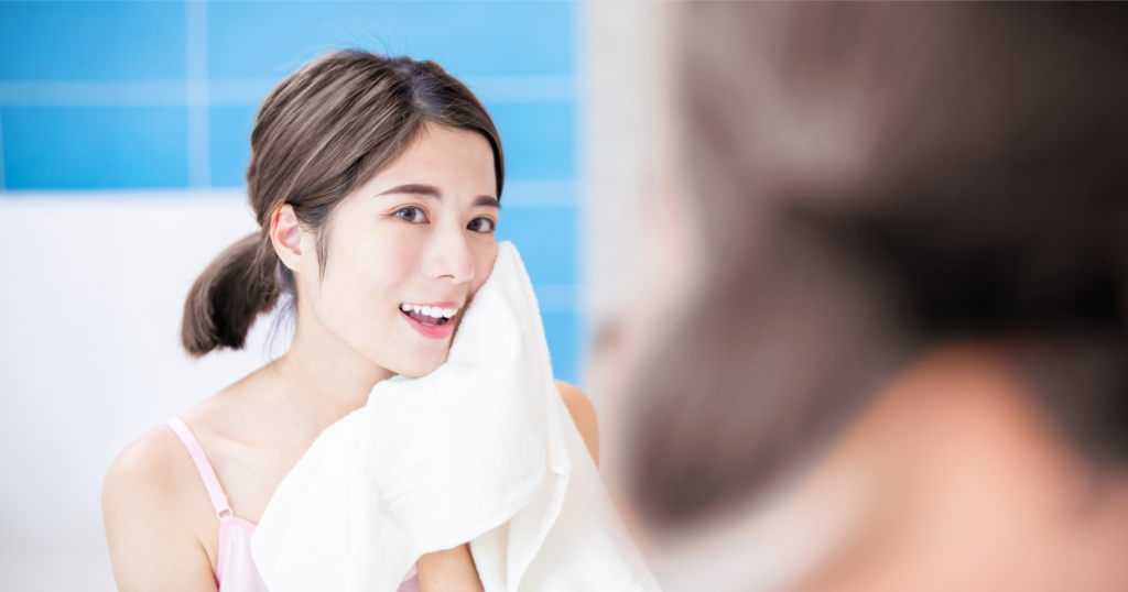 洗顔終わりにタオルで顔を拭きながら鏡で顔を確認している様子